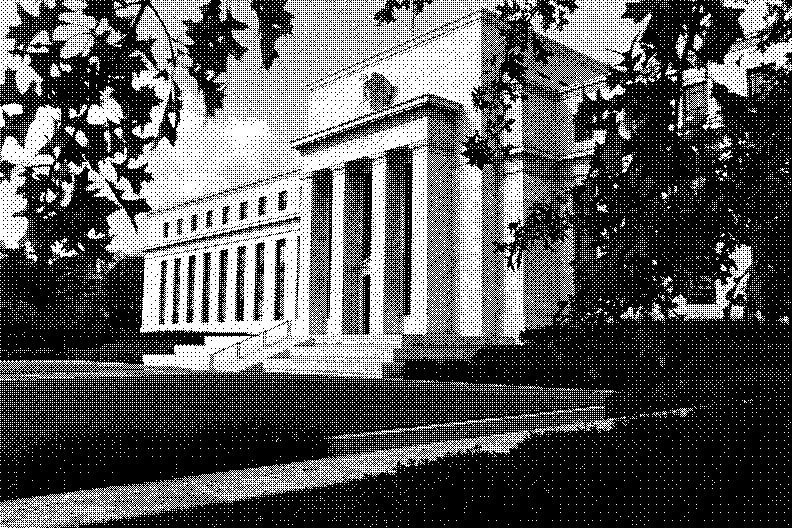 The columned front of the Federal Reserve Board building in Washington, framed by trees