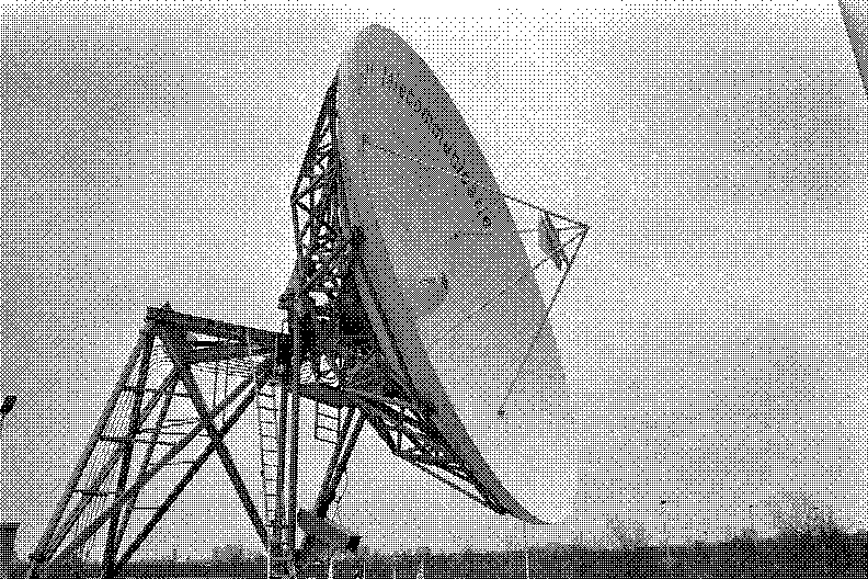 A large satellite dish on a steel frame against a grey sky, at the Teleport in Amsterdam in 1986